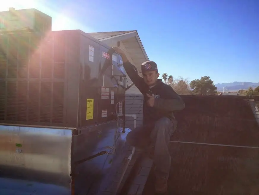HVAC technician performing Air Duct Cleaning on a rooftop unit in Burlington